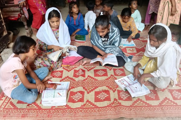 Four schoolchildren sat studying in a basic classroom setting