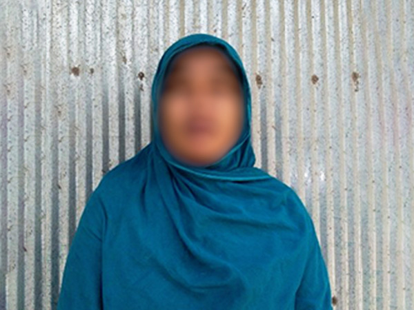 A woman wearing blue headcovering in front of a metal wall