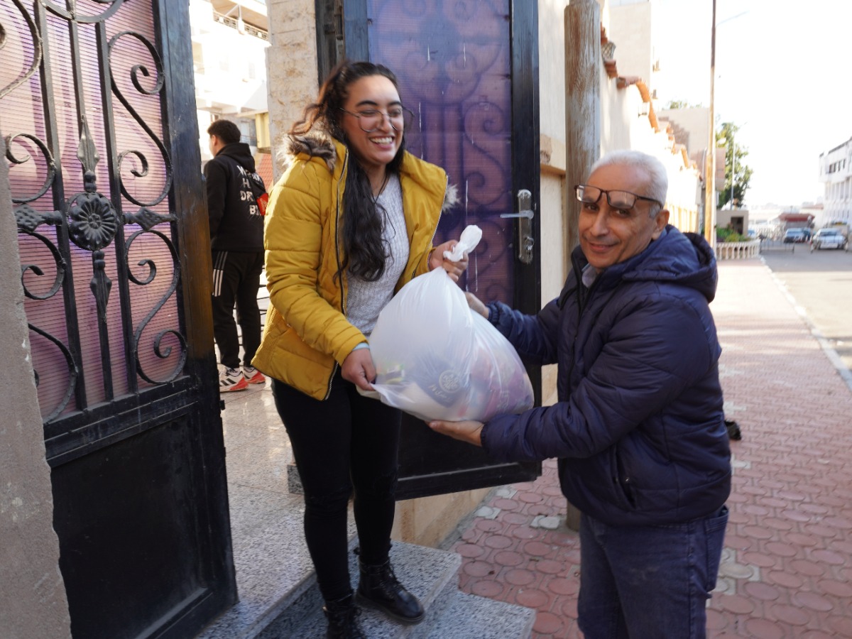 A man hands a bag of aid to a woman