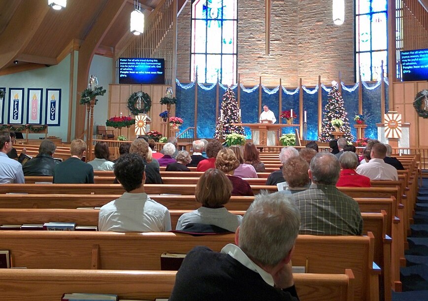 People sitting inside church decorated for Christmas