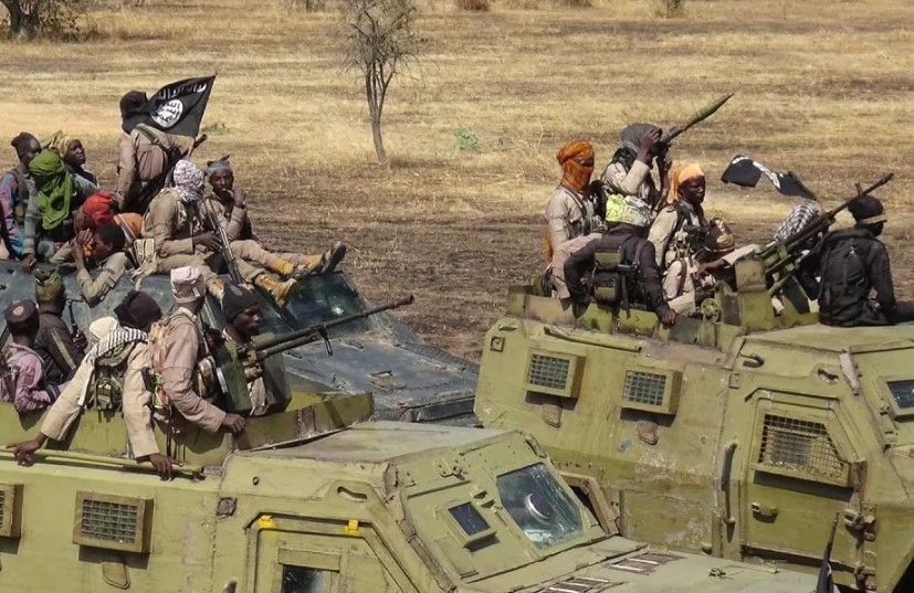 Men with guns and black flags riding armoured vehicles