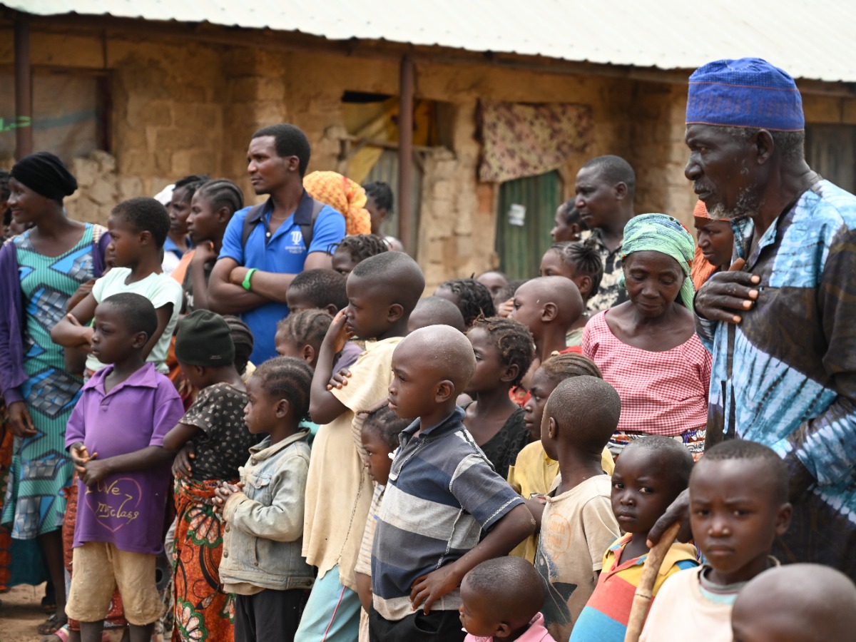 A group of men, women and children in an impoverished setting