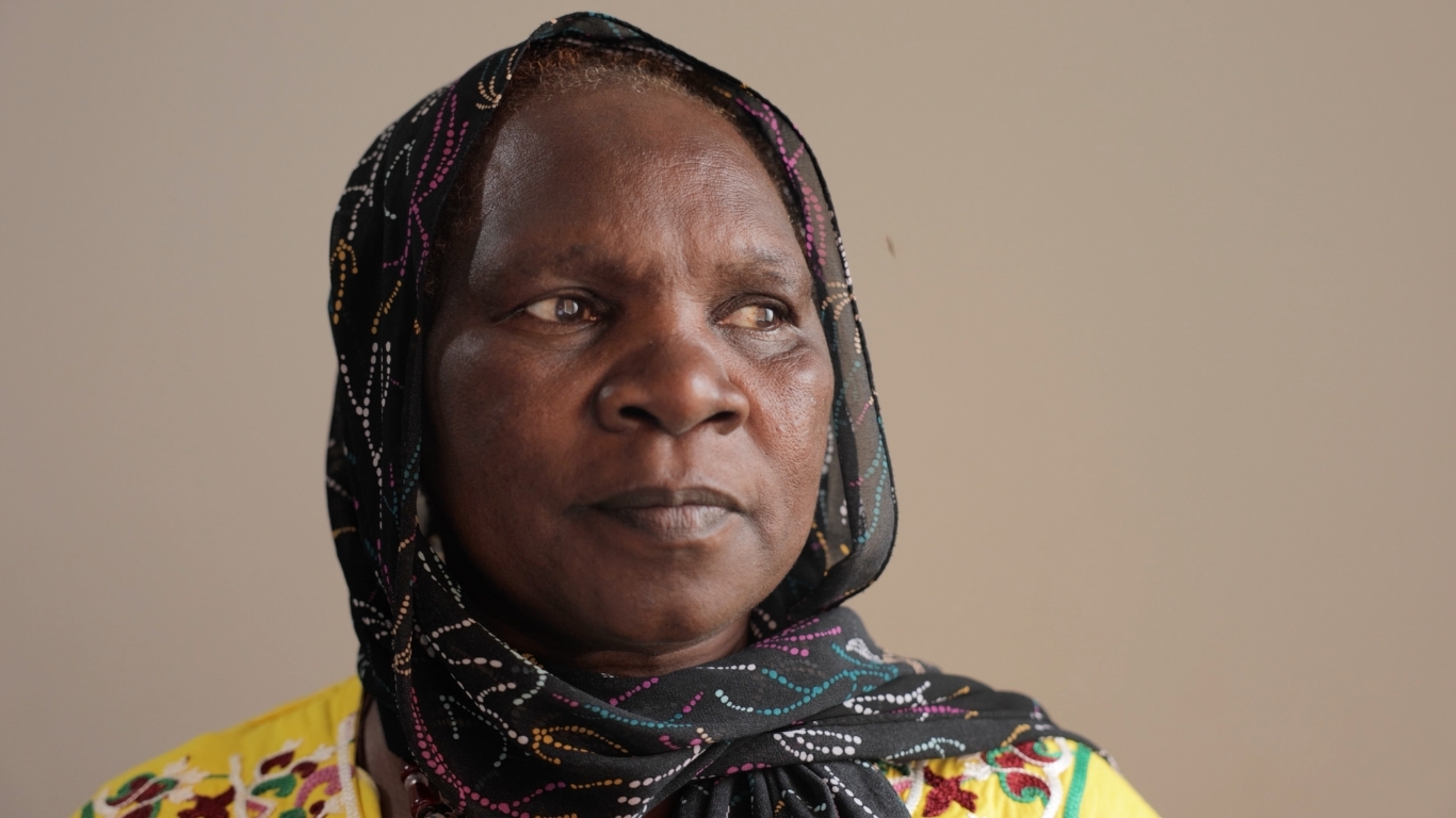 Sudanese Christian woman wearing a red shawl is visibly crying, conveying a sense of sadness and distress.