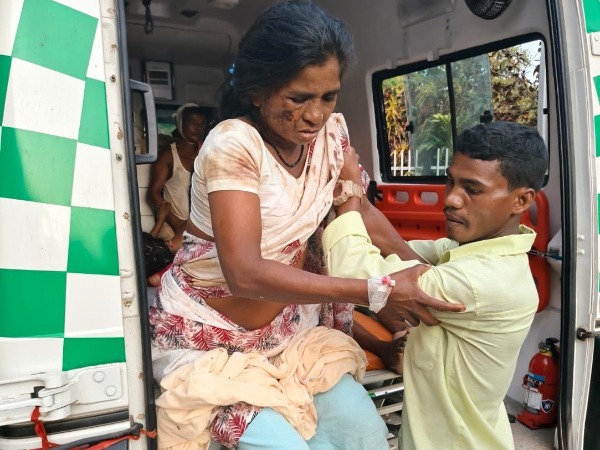 An injured woman is helped out of the back of an ambulance by a young man