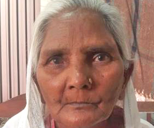 An elderly woman with grey hair and a headscarf