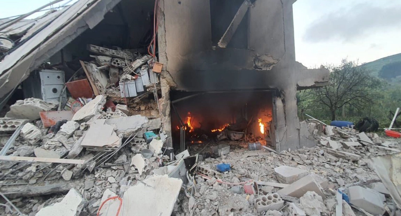 A fire burning in the rubble of a destroyed building
