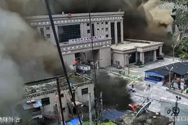 A wall of water and debris engulfs a large building