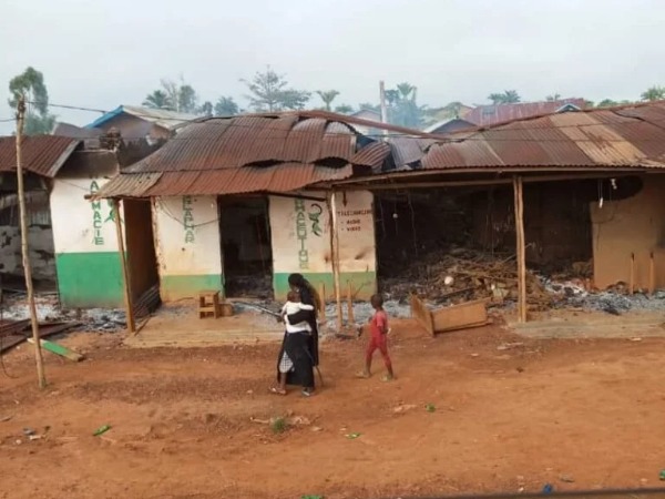 A woman with two young children in front of a damaged building
