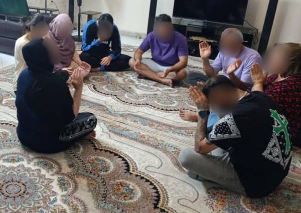 A group of people sat cross-legged in a living room