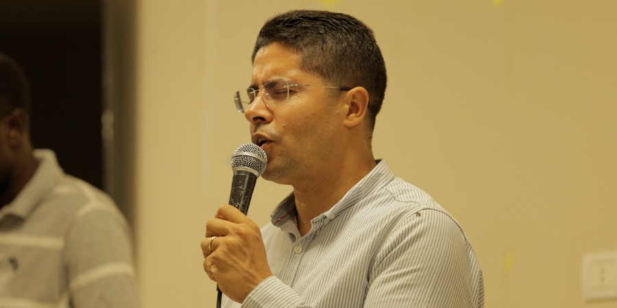 A young man wearing glasses speaks into a microphone