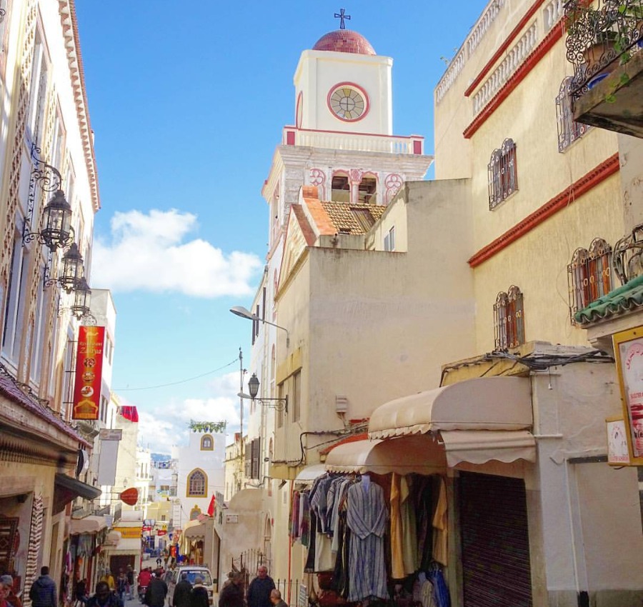 A spire above a busy street on a clear, sunny day