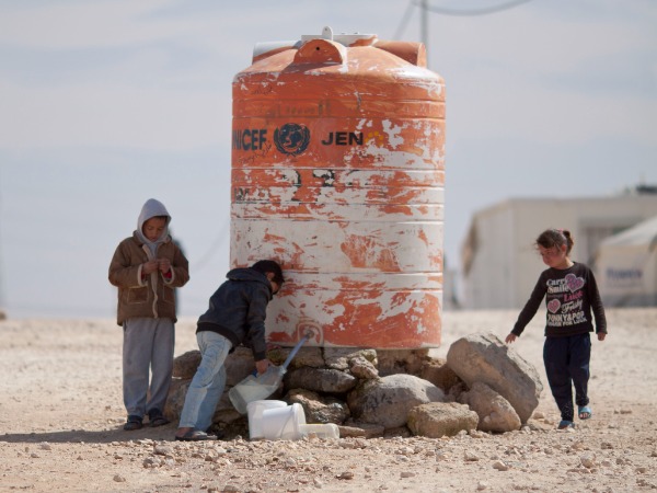 Children around a large water container in the desert