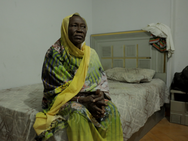 A woman in traditional clothes seated on a bed