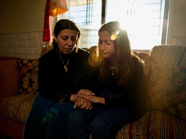 A mother and her adult daughter pray together