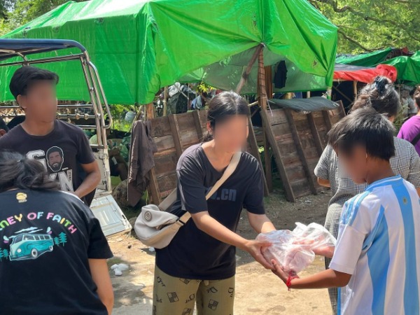 A woman hands a bag to a young boy