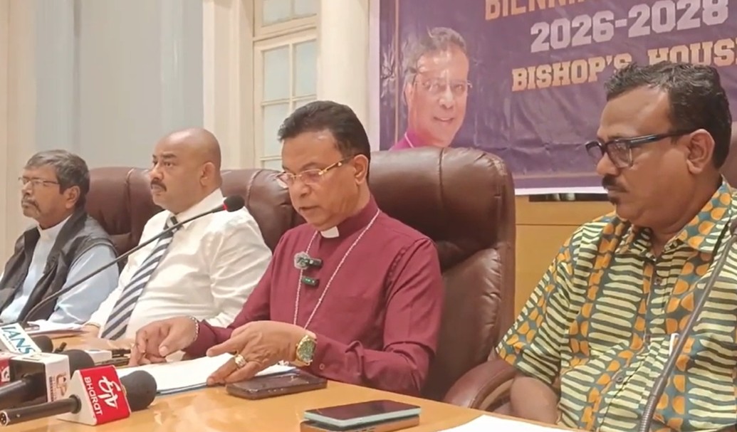 Four men sat behind a desk, with one speaking into a microphone