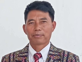 A middle-aged man dressed in patterned jacket and tie