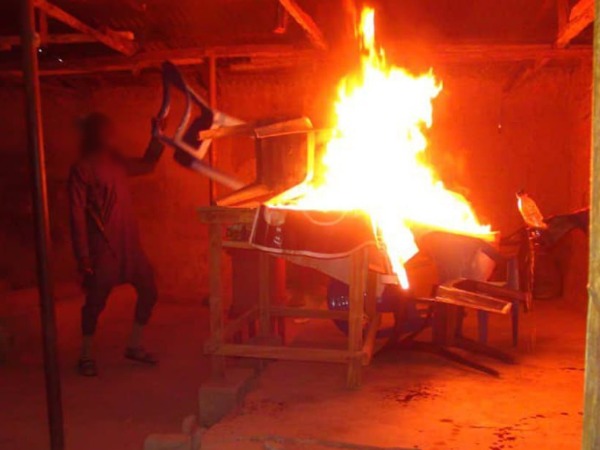 A man throws a chair onto a fire on a lectern
