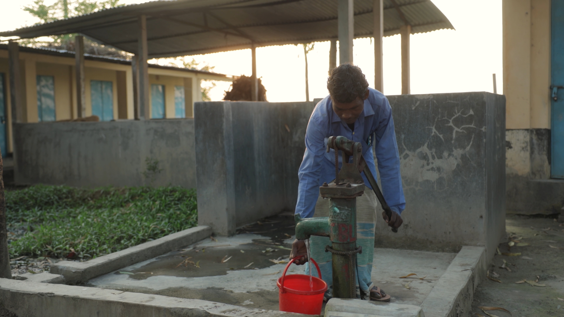 Dijen fills a bucket of water