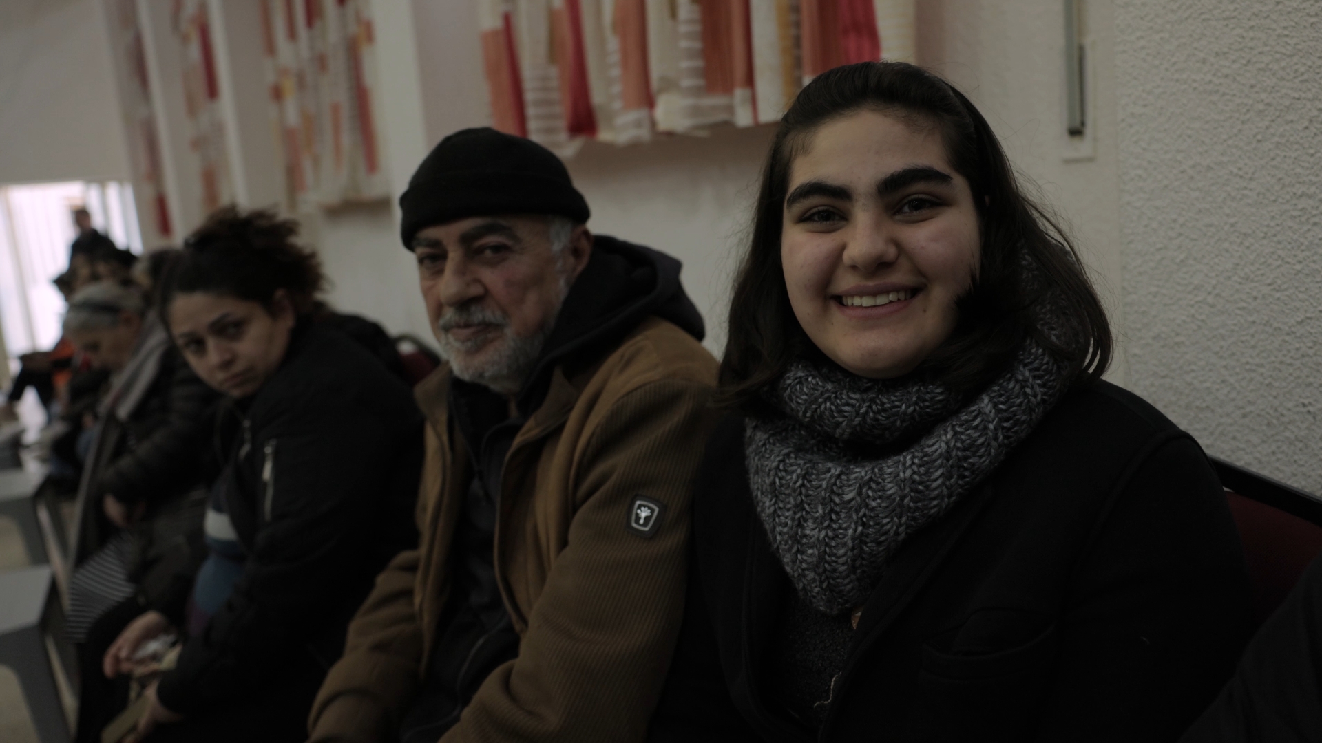 Christian men and women are seated together, waiting in line for food aid in Jordan.