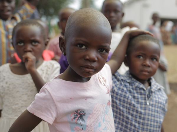 A young girl in a pink tee-shirt with a younger boy in checked shirt
