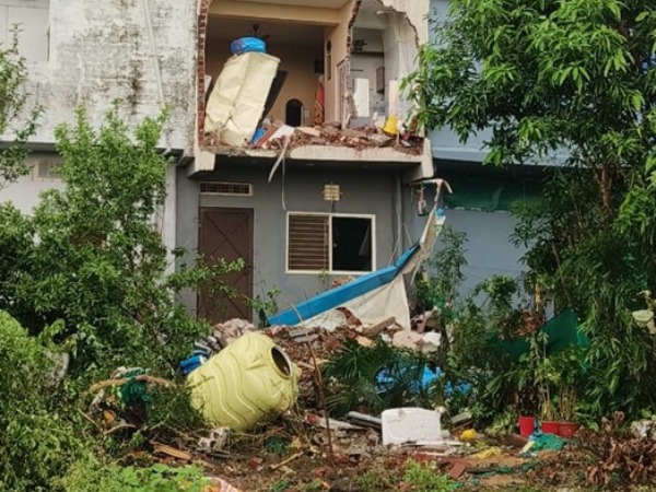 A pile of rubble in front of a house with broken walls and damaged interior