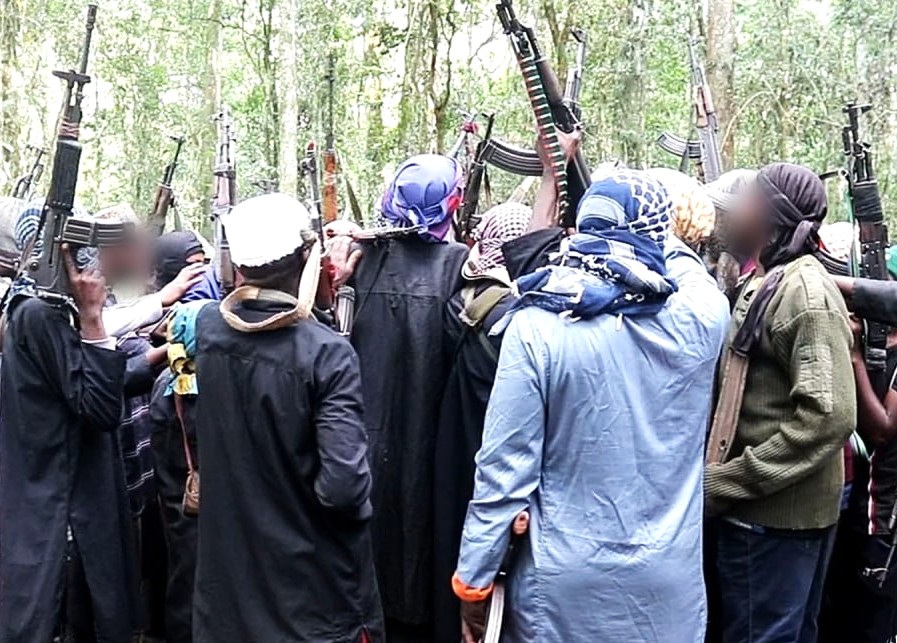 Men standing in a forest pointing guns in the air