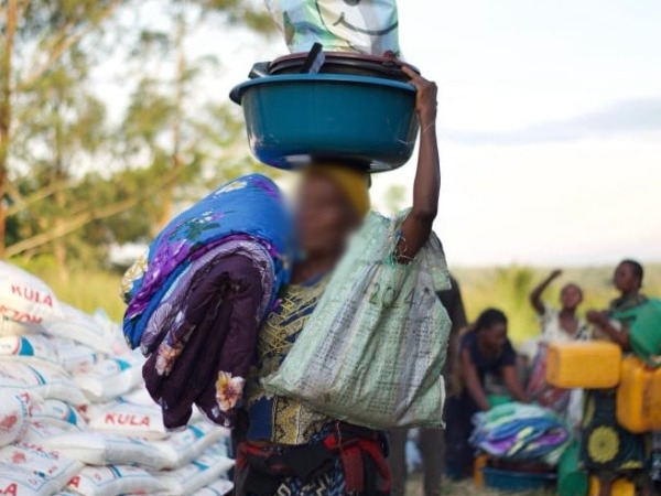 A woman carrying blankets and bags
