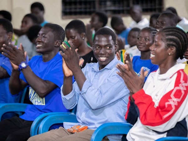 A congregation in chairs, hands raised in worship, reflecting a spiritual gathering in Ghana.