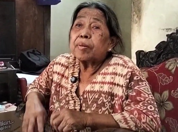 An elderly woman looks to camera