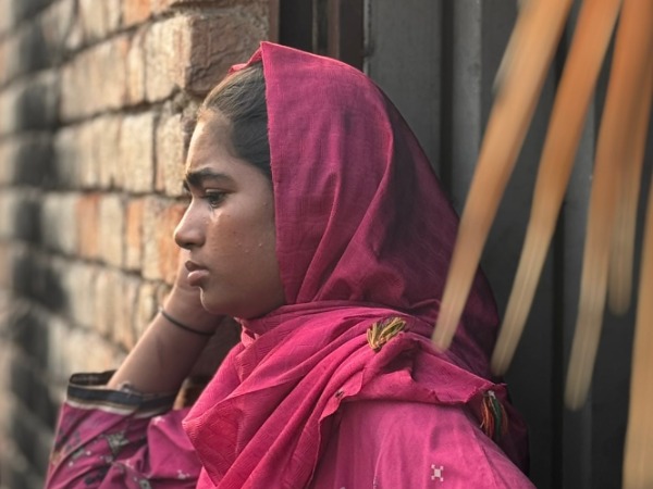 A young women wearing a pink headscarf looking sad and tearful