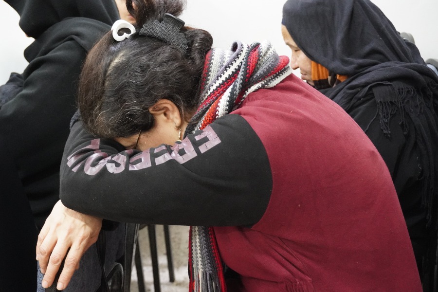 A woman in church rests her head on her folded arms