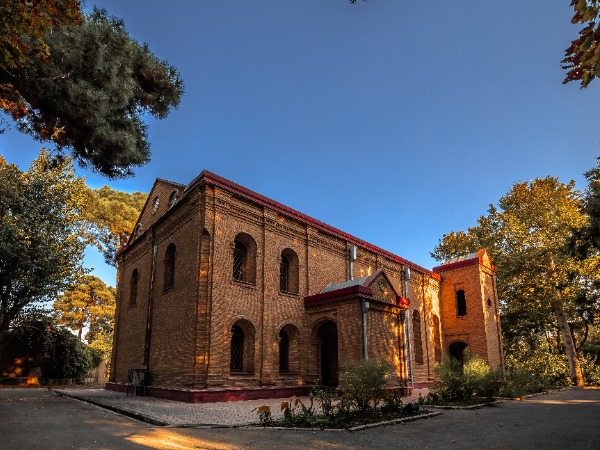 Red brick church building set amongst some trees